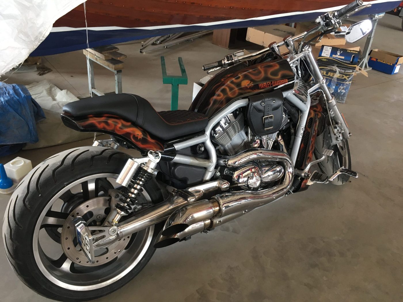 Harley-Davidson leegimustriga mootorratas musta nahksadulaga töökojas.