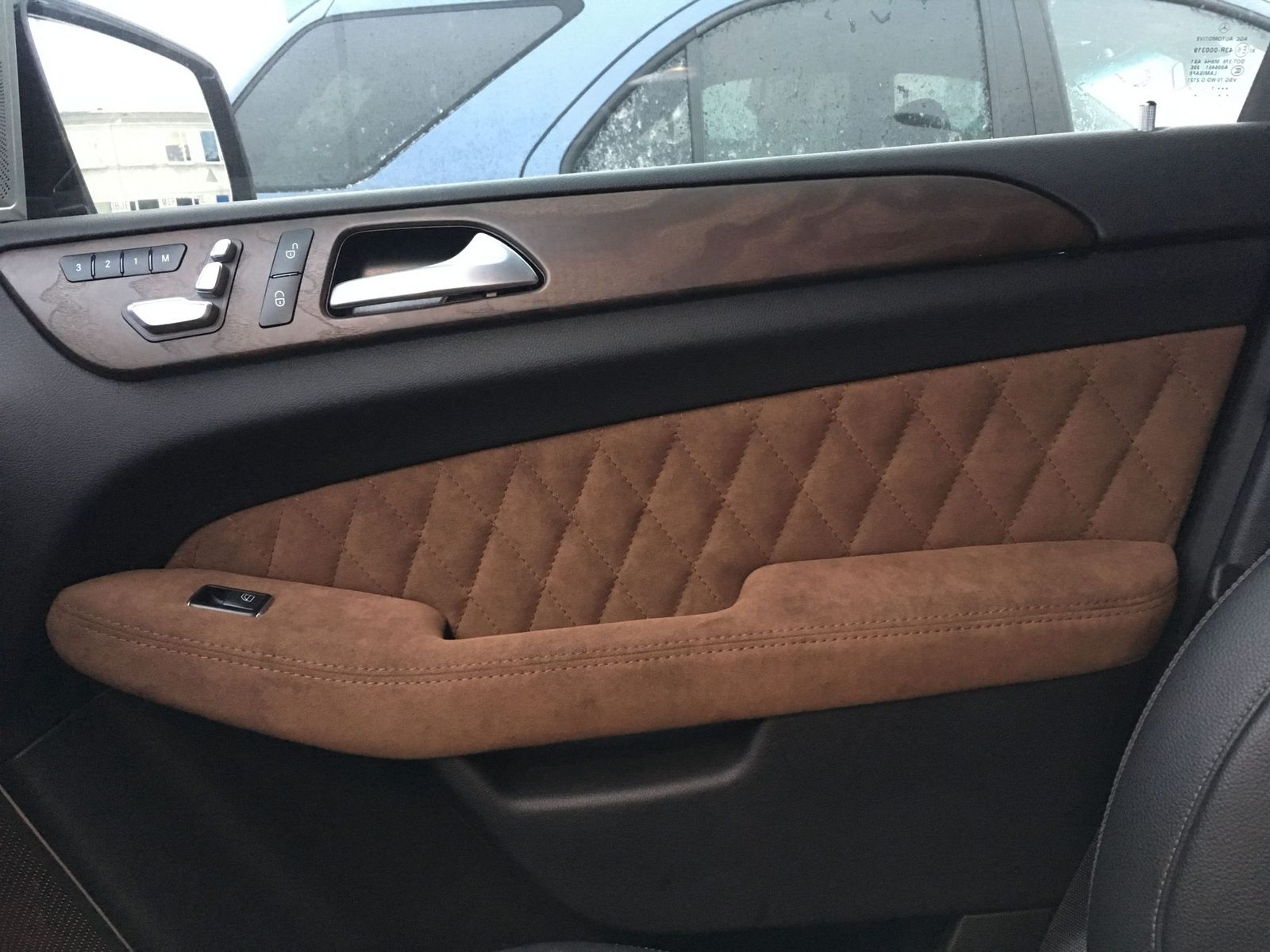 Mercedes-Benz GL uksepolster: konjakipruun seemisnahk rombtepiga, puitliist ja kroomitud käepide.